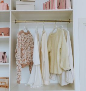 A white closet with clothes on hangers and purses