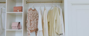 A white closet with clothes on hangers and purses