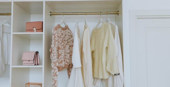 A white closet with clothes on hangers and purses