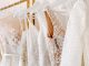 Collection of wedding gowns featuring lace, sequins, and embroidered details displayed on a boutique clothing rack.